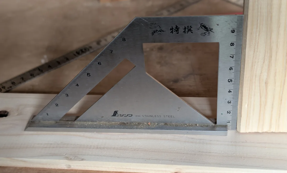 シンワ測定 62081を直立した家具へ当てて直角を確認している様子